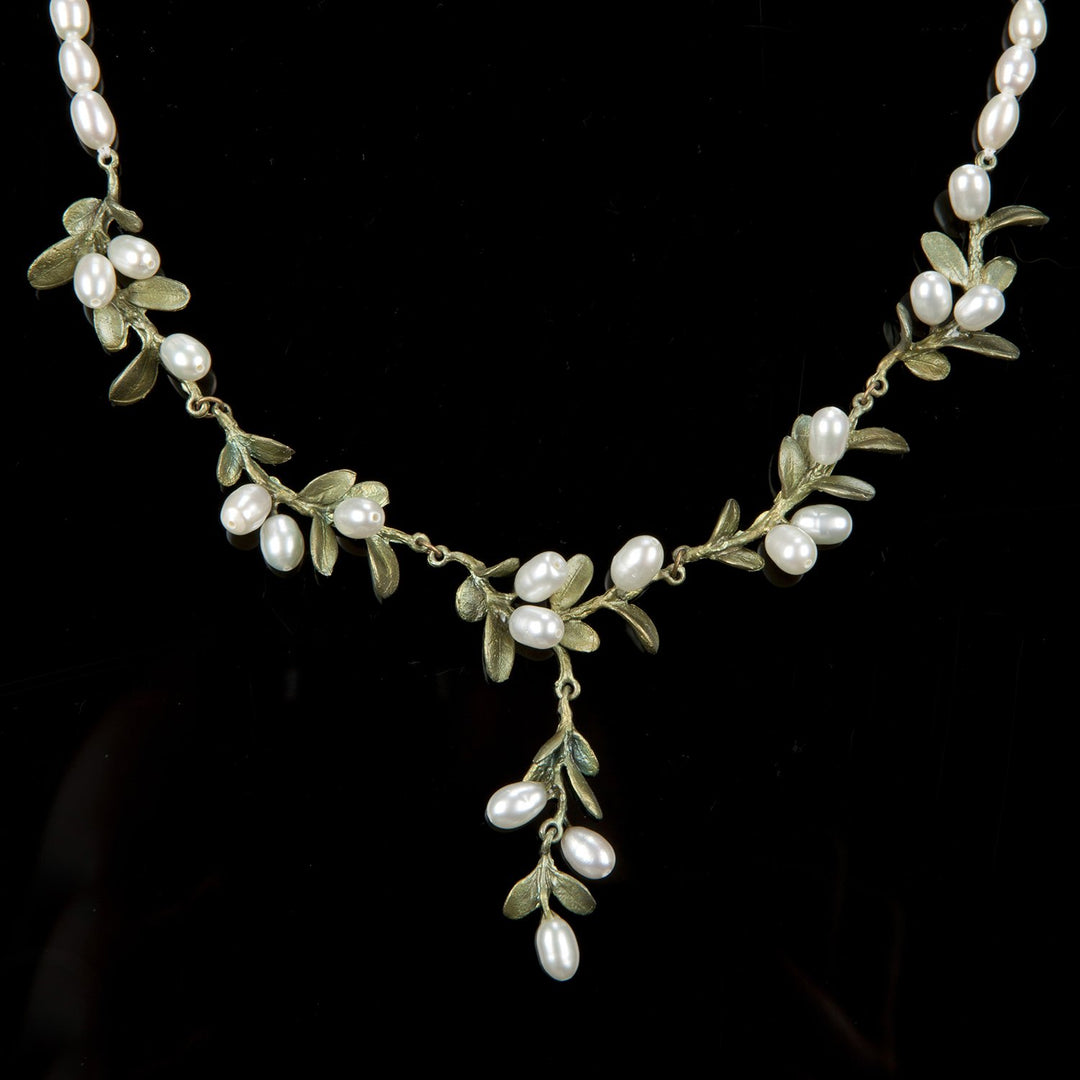 Delicate necklace with small green leaves and white pearl clusters on gold-tone wire.