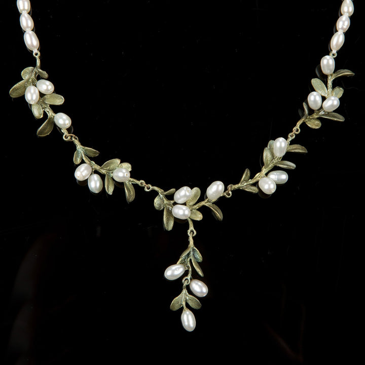 Delicate necklace with small green leaves and white pearl clusters on gold-tone wire.