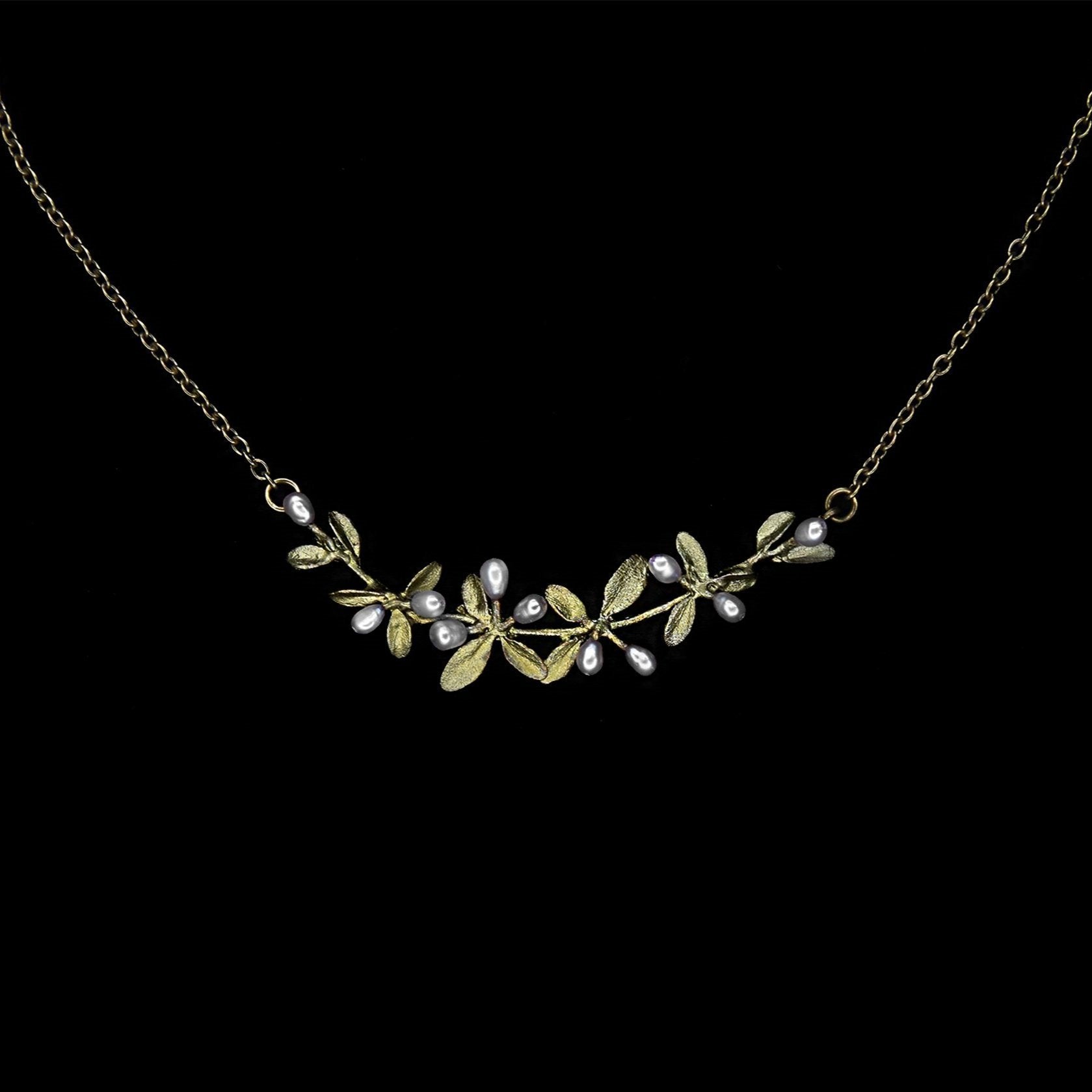 A bronze necklace with a cluster of small leaves and white pearl accents, set against a black background.