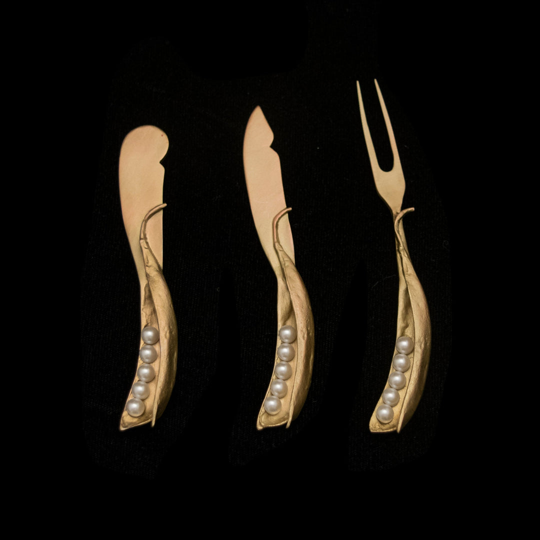 A set of three hostess utensils with gold-colored handles and pearl-like embellishments, displayed against a black background.