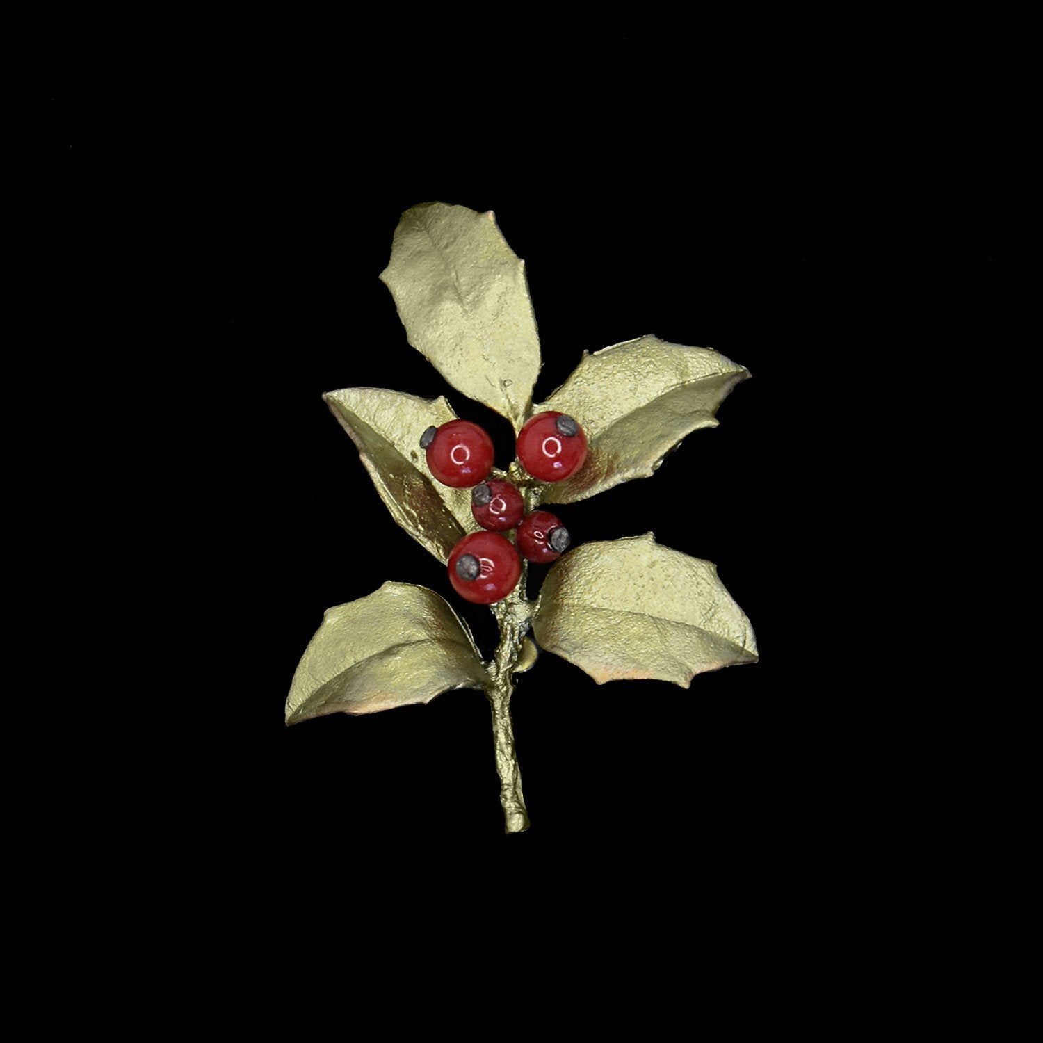 A decorative brooch shaped like a holly branch, featuring gold-colored leaves and red berry-like beads, set against a black background.