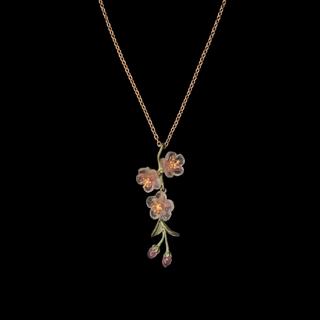 A necklace featuring a green patinated bronze pendant with cast glass flowers in pink and gold-plated centers.