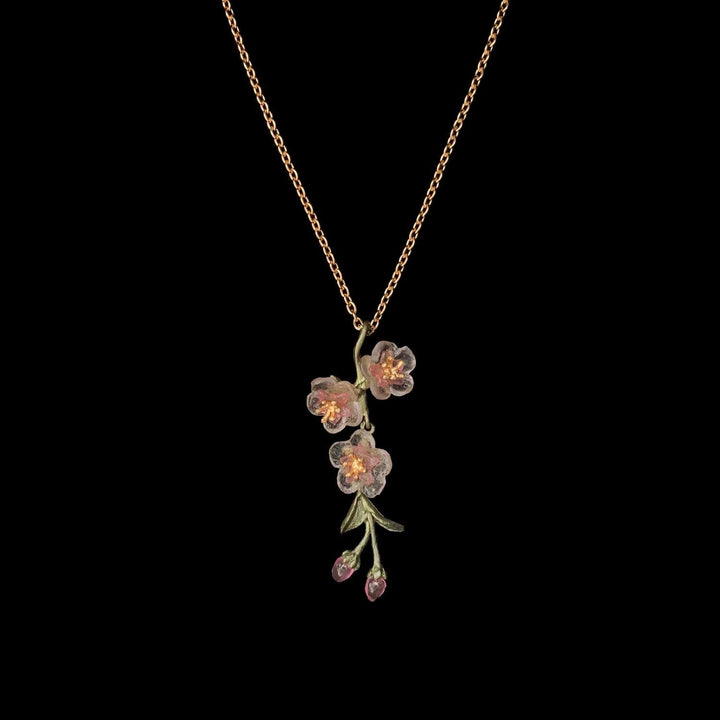 A necklace featuring a green patinated bronze pendant with cast glass flowers in pink and gold-plated centers.