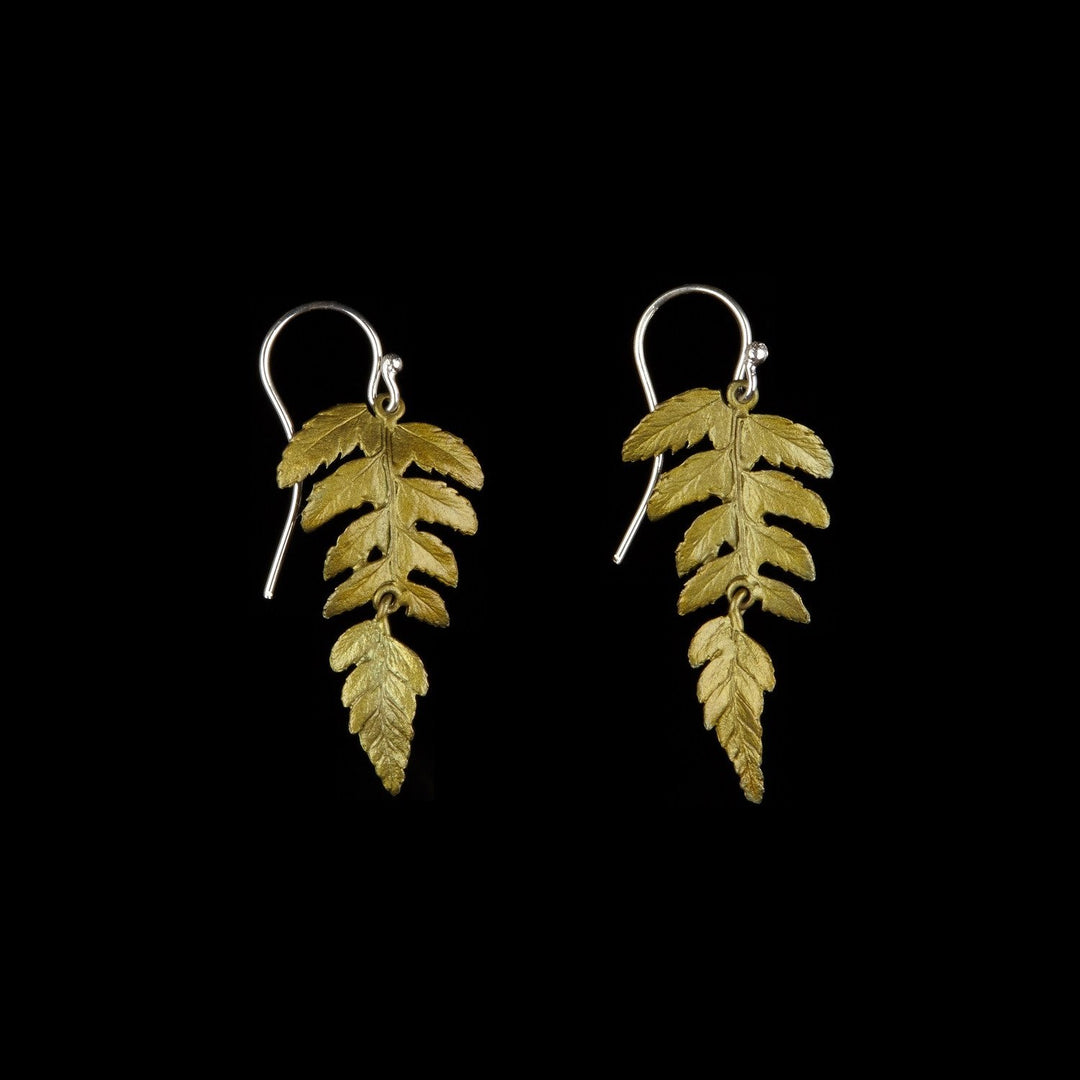 A pair of fern leaf earrings with green patinated leaves on a black background, crafted in bronze with gold plated silver hooks.