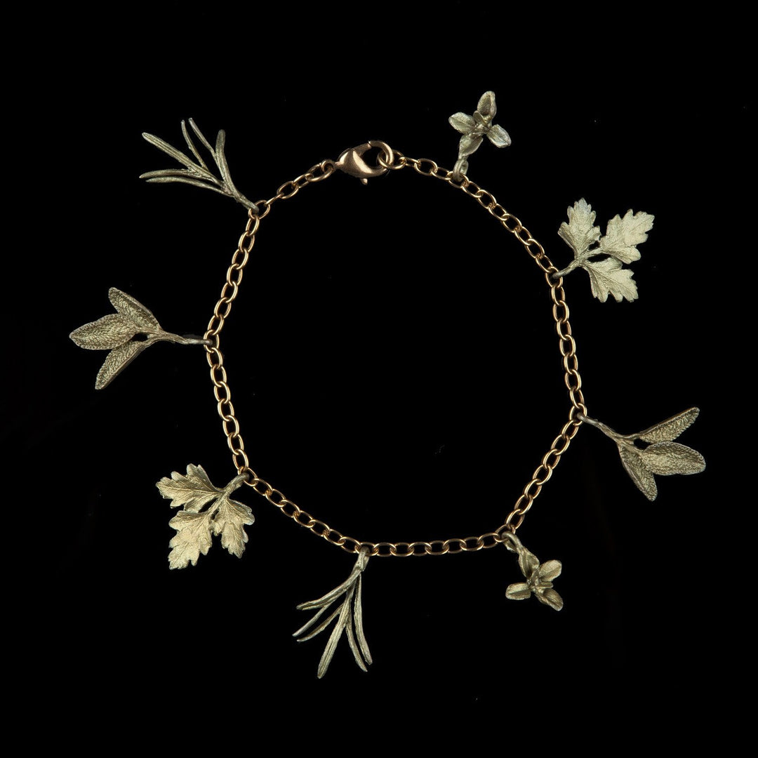 A green-tone charm bracelet featuring charms shaped like herbs, including thyme, parsley, sage, and rosemary, against a black background.