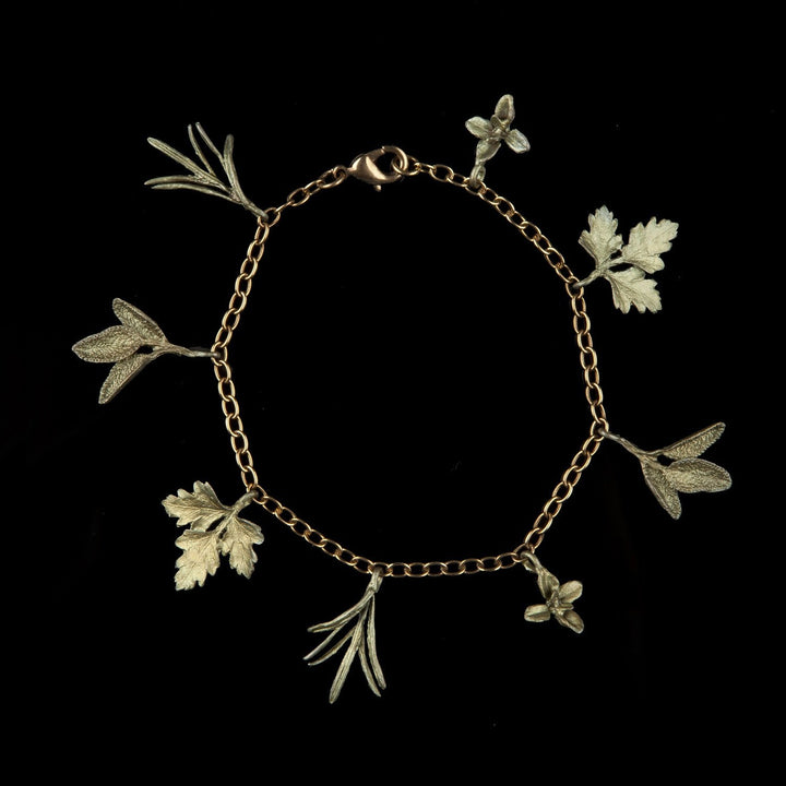 A green-tone charm bracelet featuring charms shaped like herbs, including thyme, parsley, sage, and rosemary, against a black background.